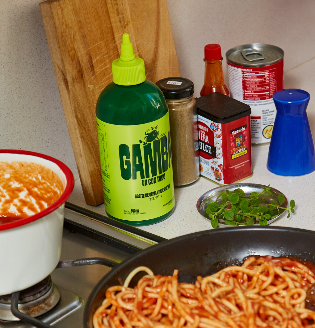 Sarten con fideos al tomate en la hornalla y la botella squeeze de Gamba al lado