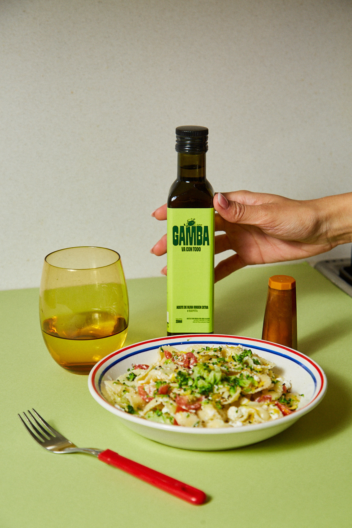 Botella de vidrio de Gamba junto a un bowl de pasta y una copa